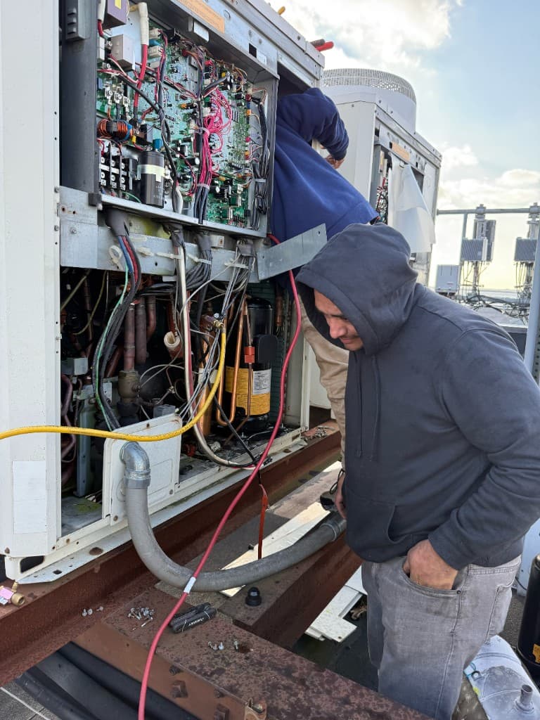 Technicians servicing commercial HVAC unit on rooftop